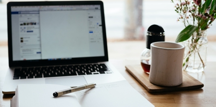 Desk with computer, open book and a coffee cup